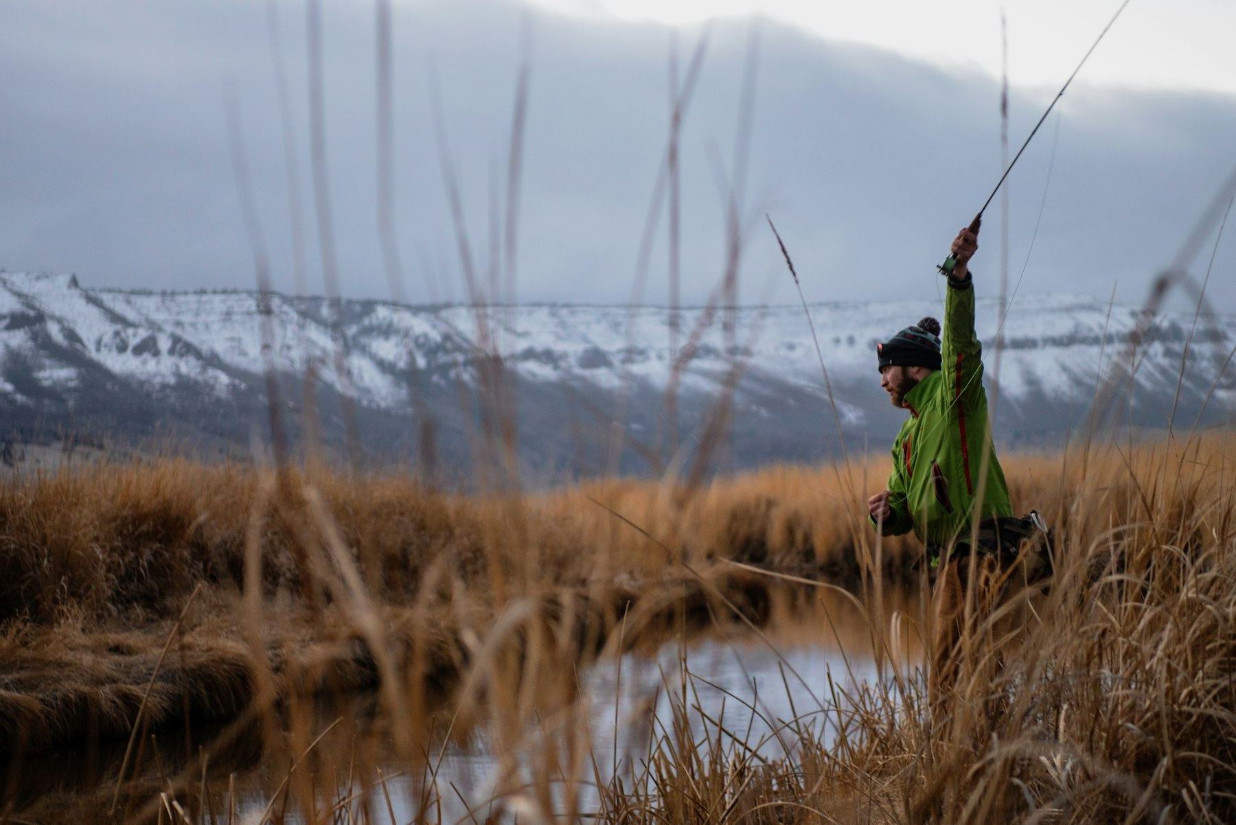 A fly fisherman standing in a mountain river at dusk
